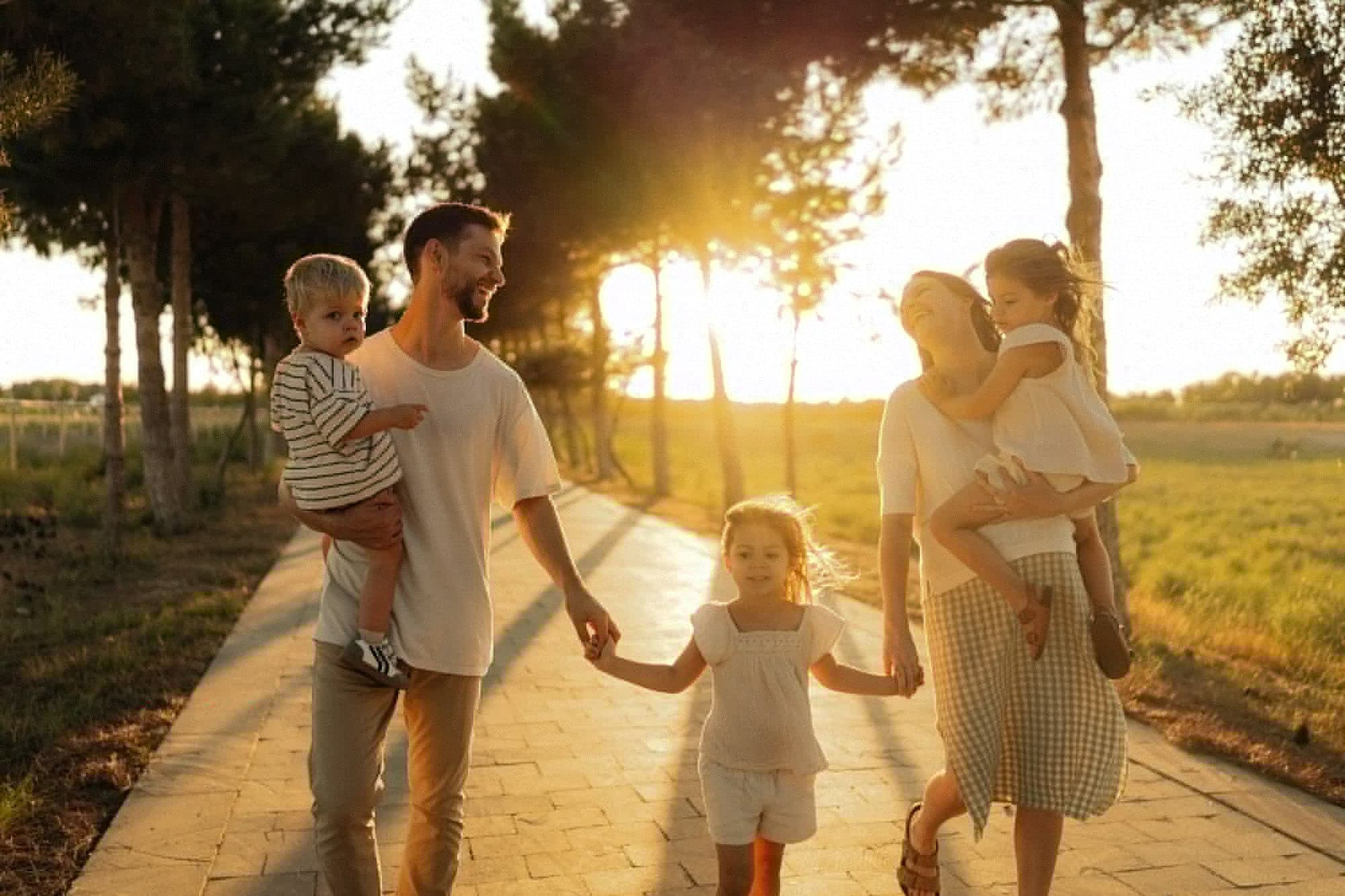 Famille de cinq marchant main dans la main au coucher du soleil