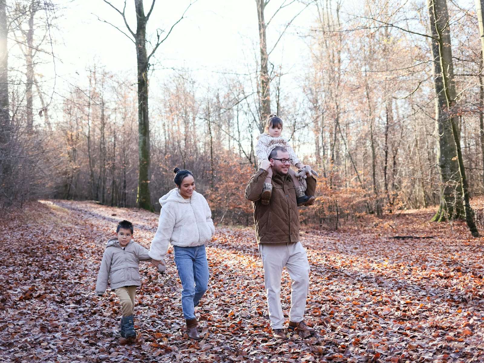 Family walking in an autumn forest, child on shoulders